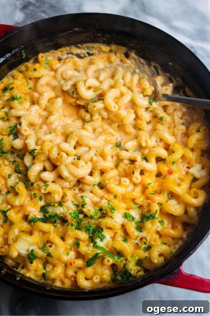 15-Minute Super Green Rigatoni Recipe for Quick Weeknight Dinner 15 Spicy mac and cheese in a large black skillet with a serving spoon inside.