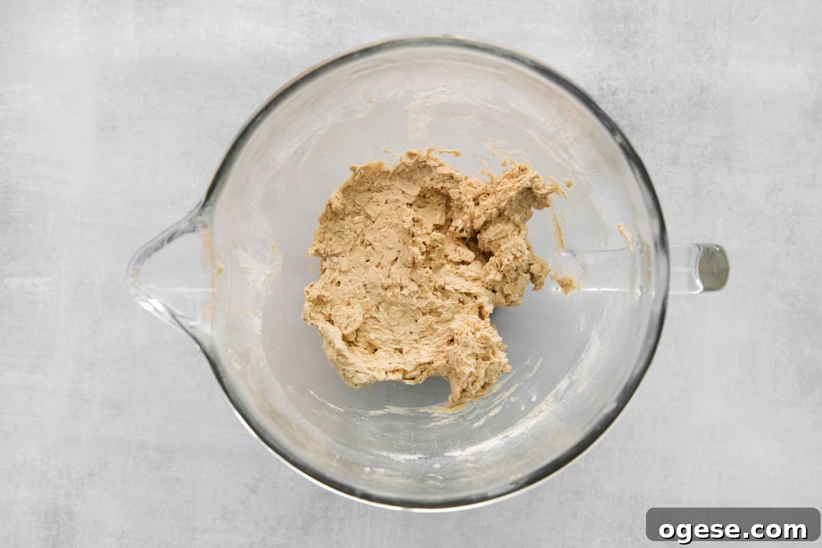 Hearty Cowboy Cookie Recipe with Oats, Chocolate & Nuts 7 peanut butter in a glass bowl on a grey background.