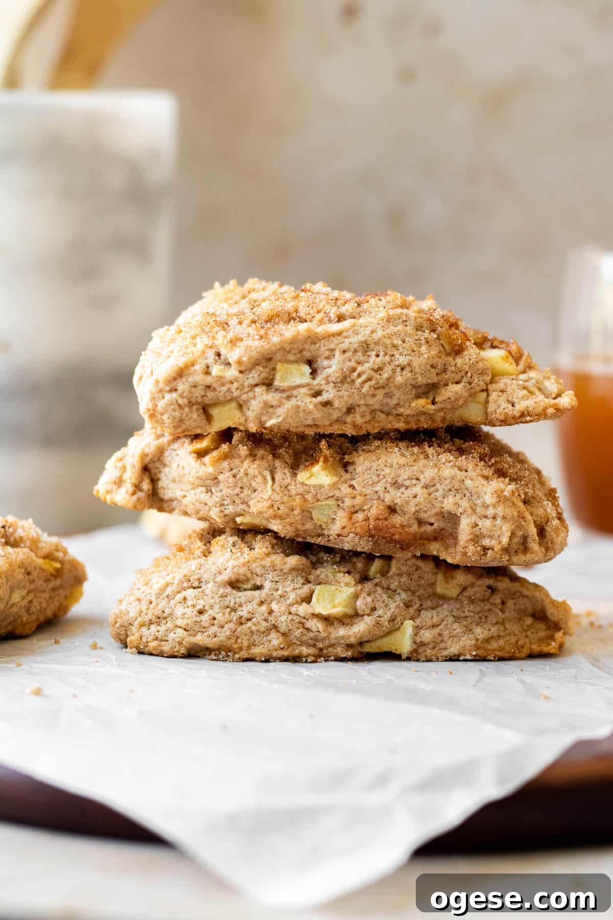 Apple Cinnamon Scones with Crunchy Cinnamon Topping 3 stack of apple scones on a parchment lined wooden cutting board with a marble utensil holder in the background
