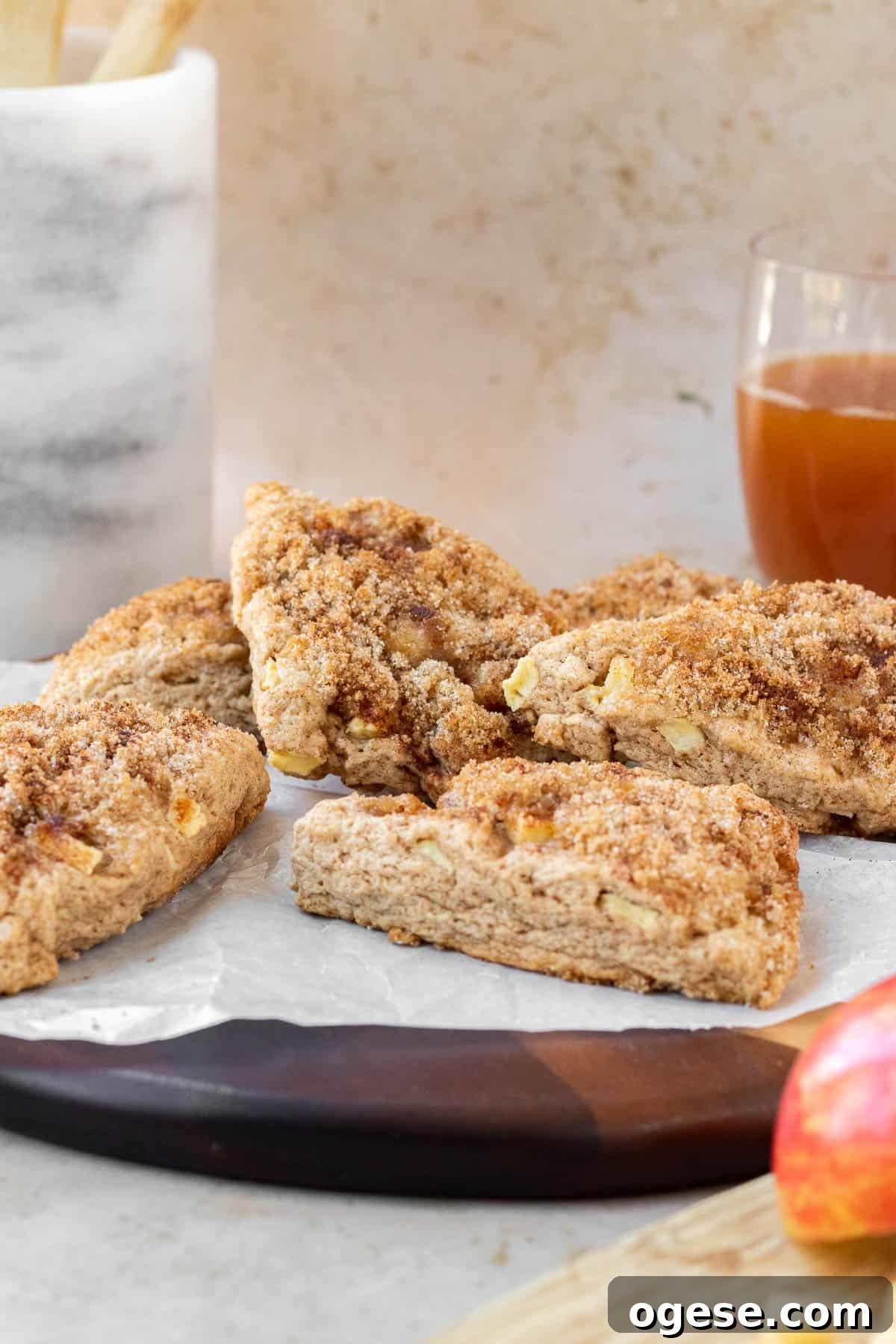 Apple Cinnamon Scones with Crunchy Cinnamon Topping 7 apple cinnamon scones on a wooden cutting board with a glass of apple cider in the background