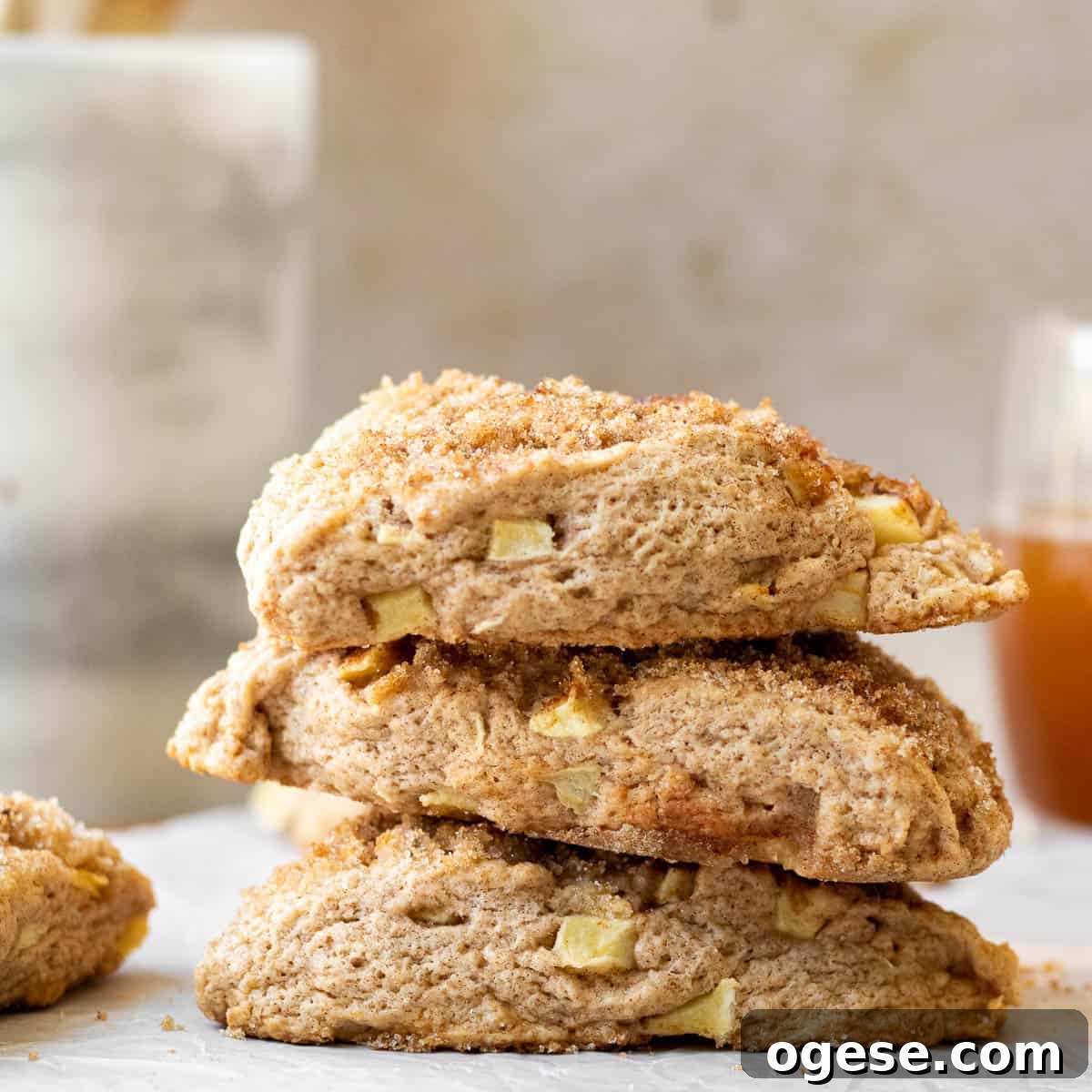 Apple Cinnamon Scones with Crunchy Cinnamon Topping 8 stack of apple scones on a parchment lined wooden cutting board with a marble utensil holder in the background