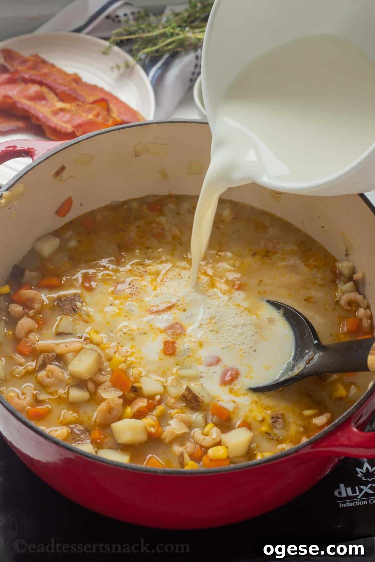 Pouring milk flour mixture into red pot of corn and shrimp chowder.