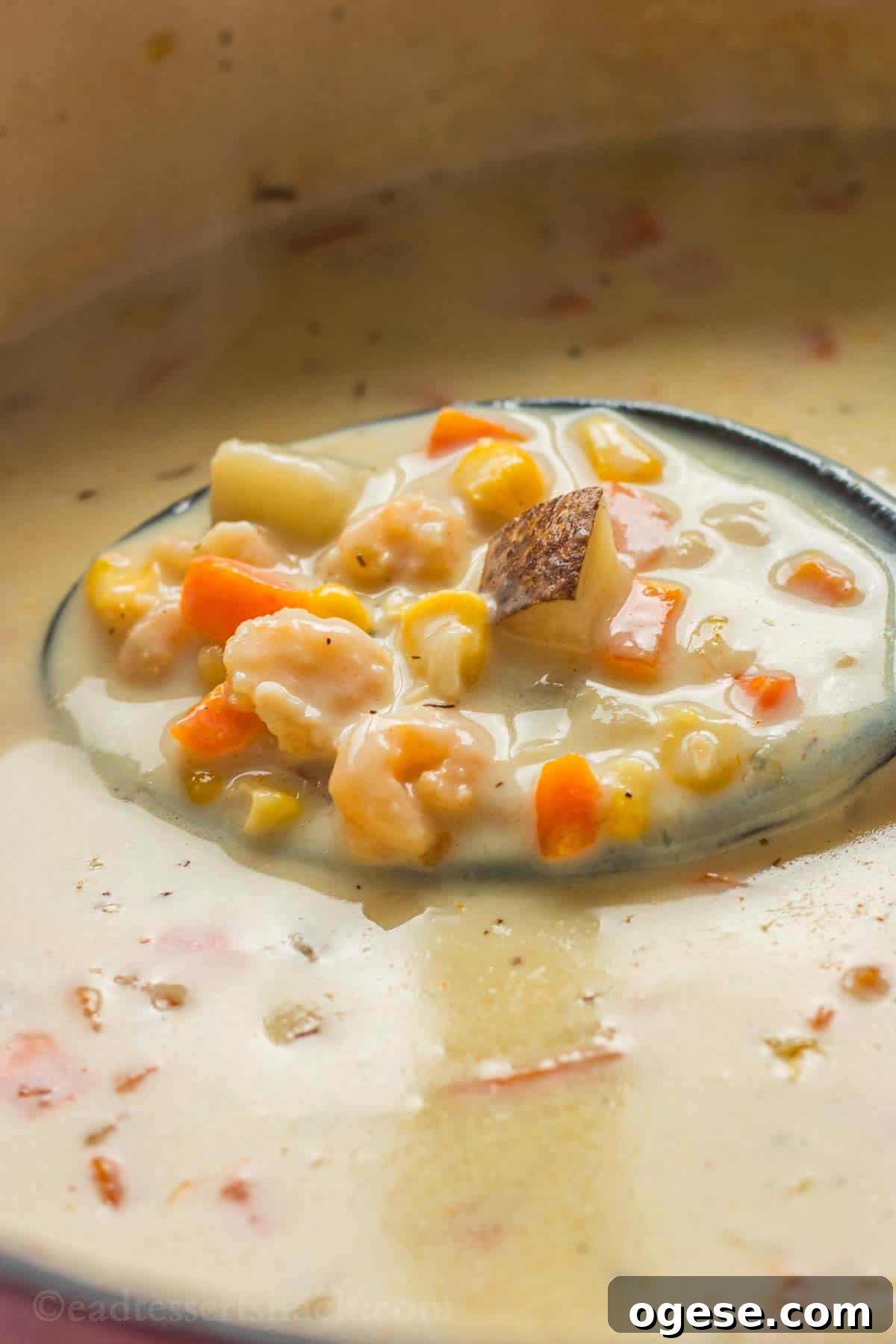 Black spoon of shrimp corn chowder in pot.