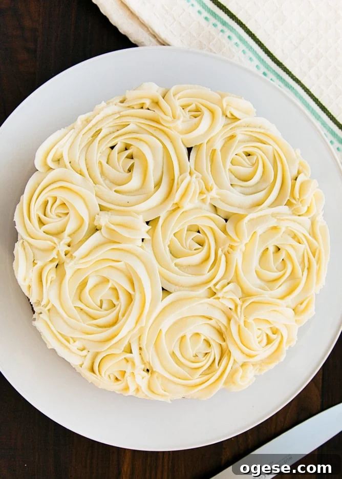 overhead photo of carrot cake piped with rosettes in cream cheese frosting on a white plate