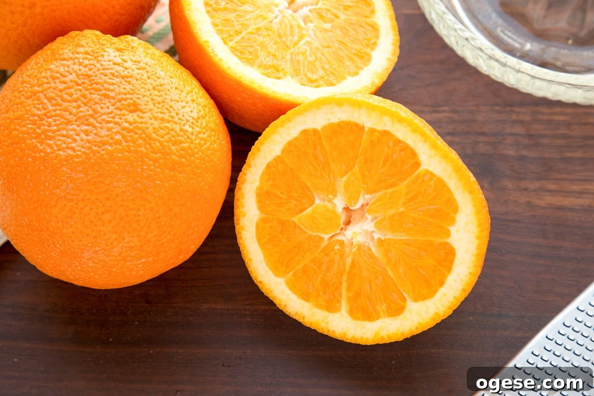 whole and halved oranges on a dark wood cutting board