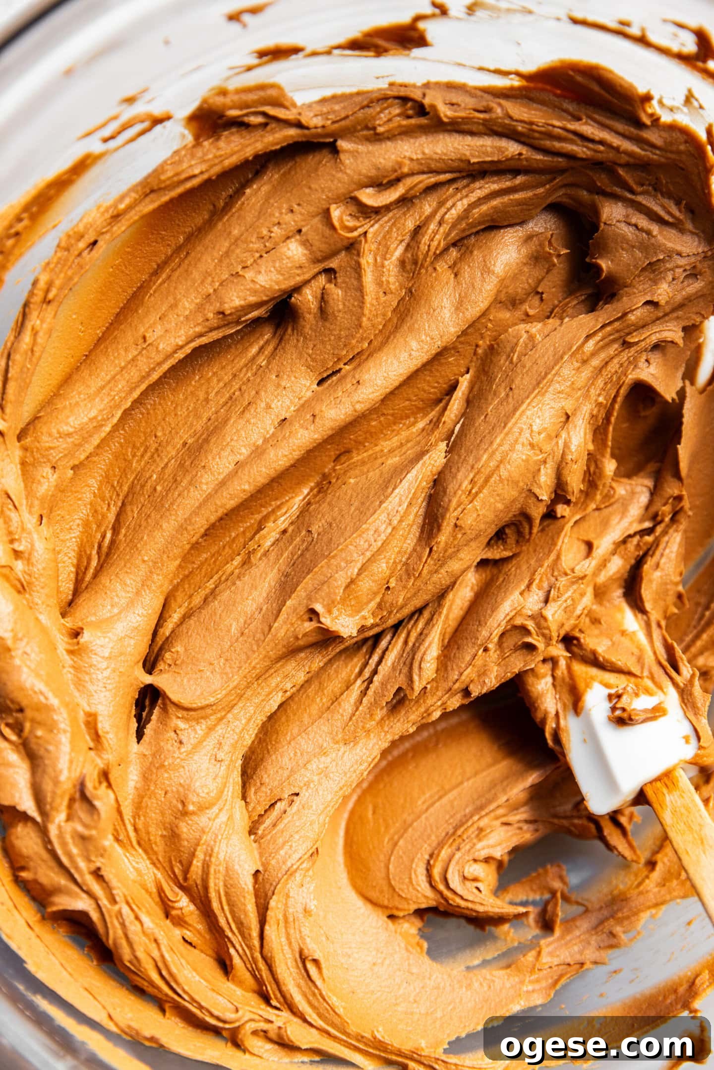 Chocolate fudge buttercream in mixing bowl with silicone spatula.
