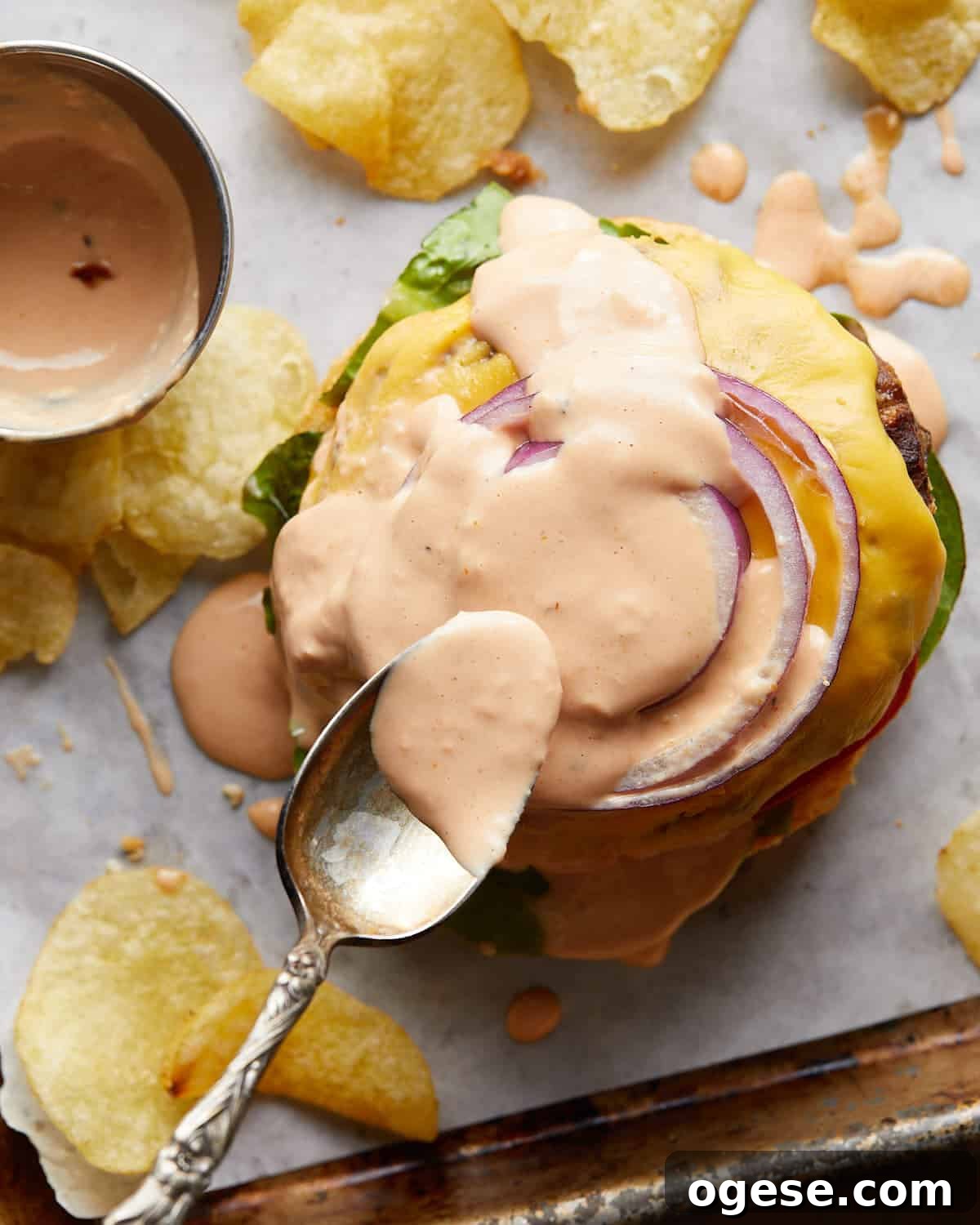 Creamy Burger Sauce Recipe Without Pickles or Relish 2 Gold spoon spreading burger sauce onto a burger.