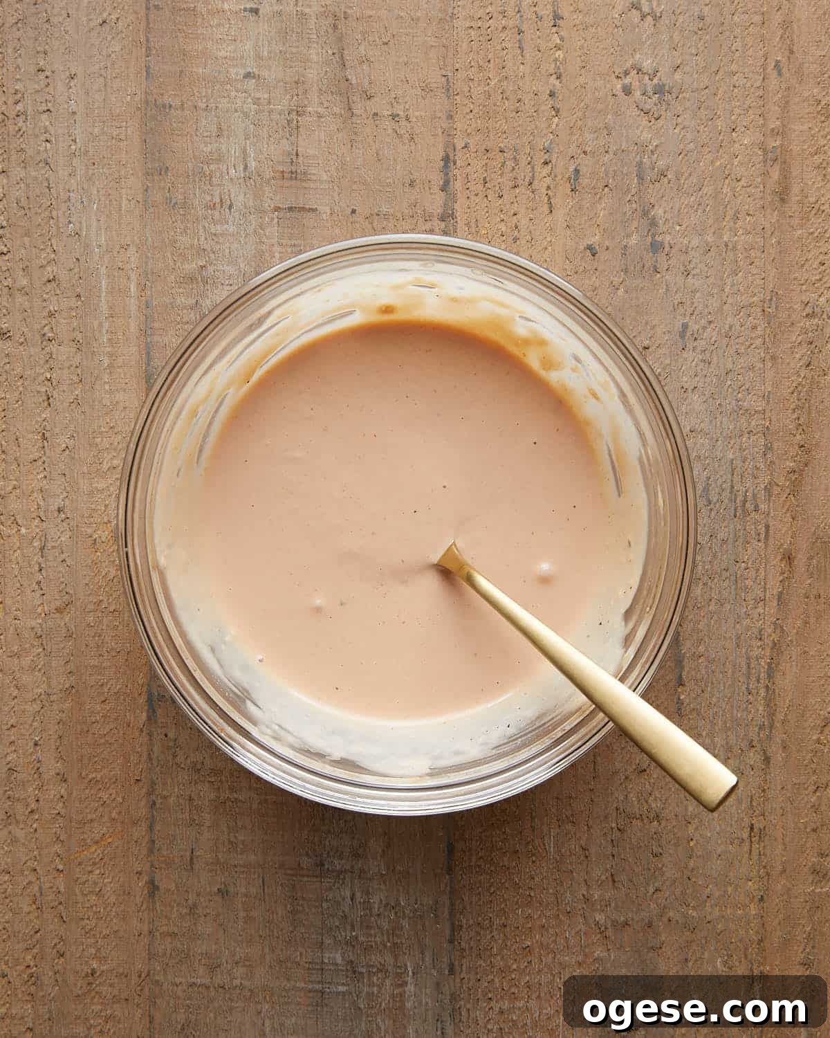 Creamy Burger Sauce Recipe Without Pickles or Relish 4 Glass bowl of creamy burger sauce mixed with a gold spoon on a wooden surface.