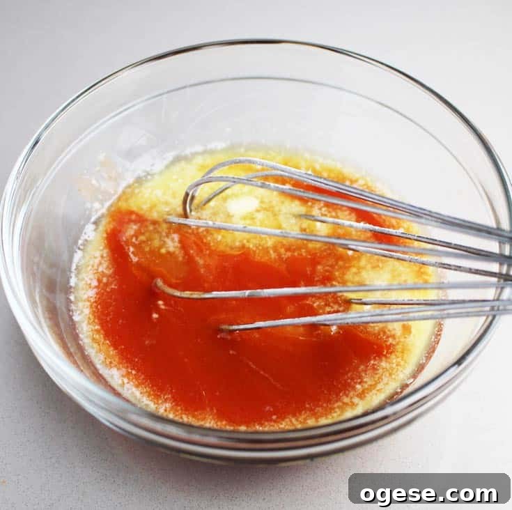 Hot sauce being whisked with butter for Buffalo chicken breast burgers