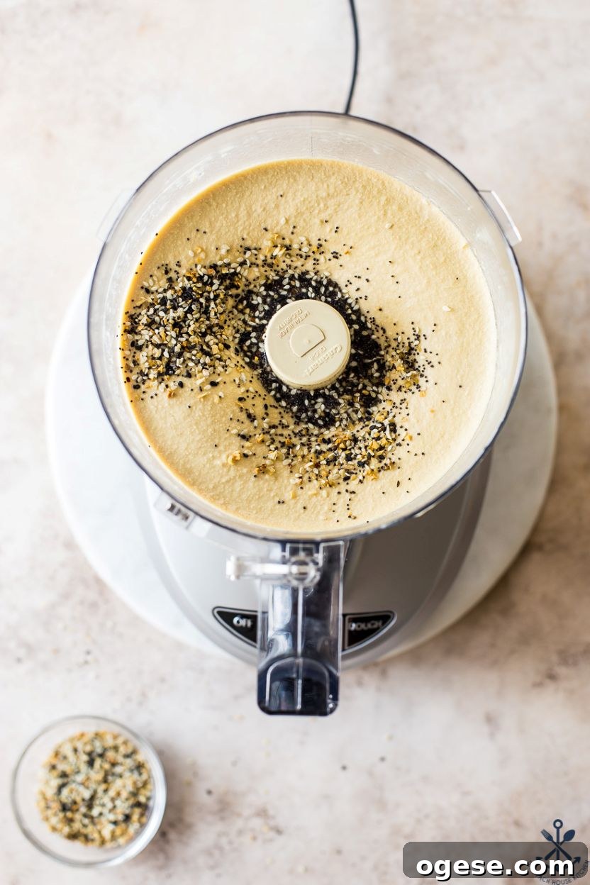 Ultimate Guide to Hummus: Recipes, Tips, and Serving Ideas 7 Overhead photo of a food processor filled with hummus topped with everything seasoning