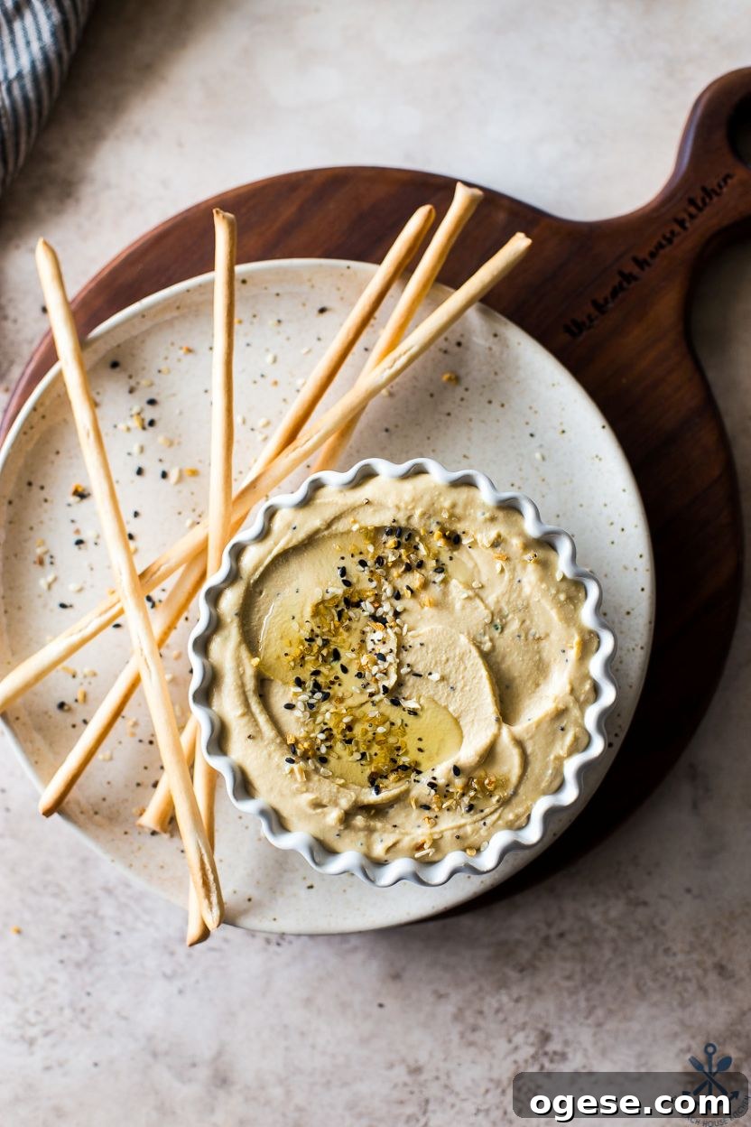 Ultimate Guide to Hummus: Recipes, Tips, and Serving Ideas 8 Up close overhead photo of everything hummus in a bowl on a plate with thin breadsticks
