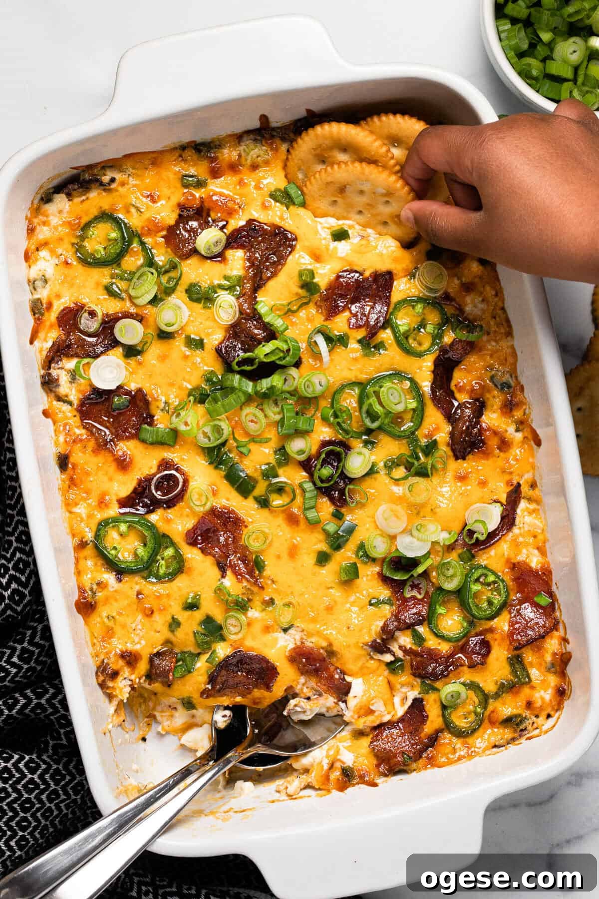 Large white baking dish filled with jalapeno popper dip with Ritz cracker scooping it up
