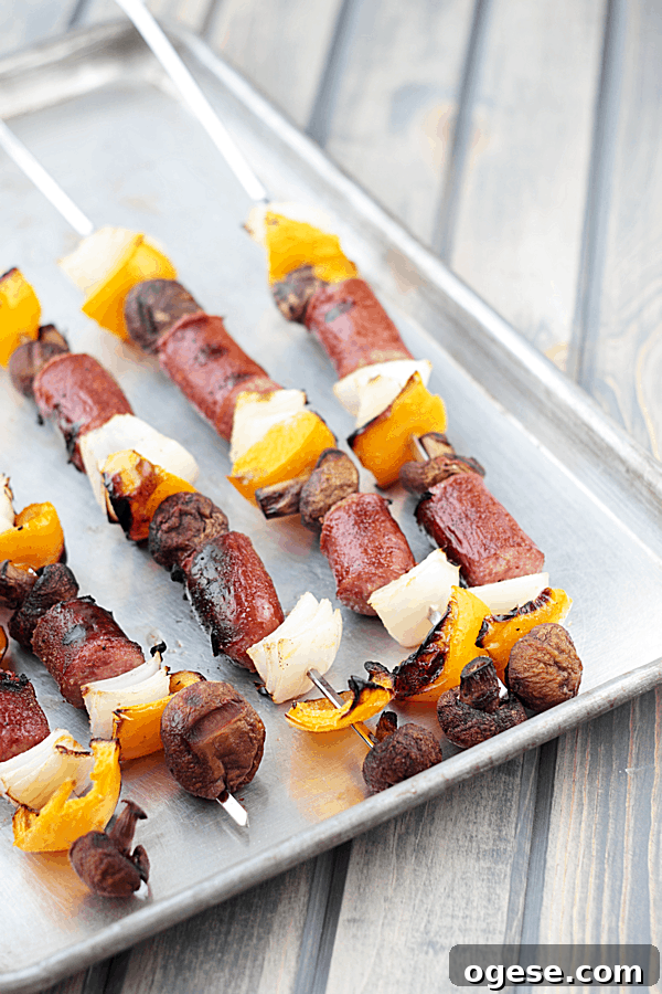 sausage and veggie skewers on a silver baking tray