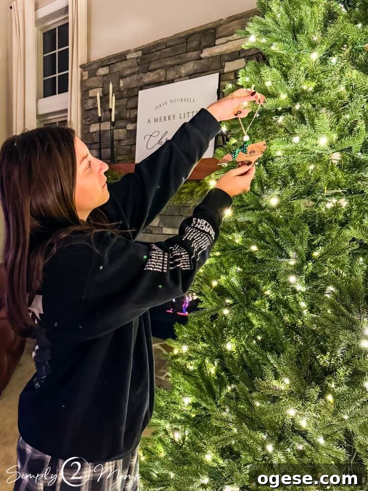 college age girl hanging ornament on Christmas tree