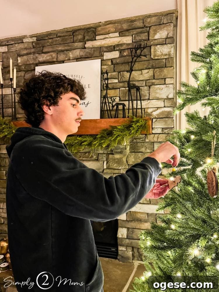 college boy hanging decoration on Christmas tree