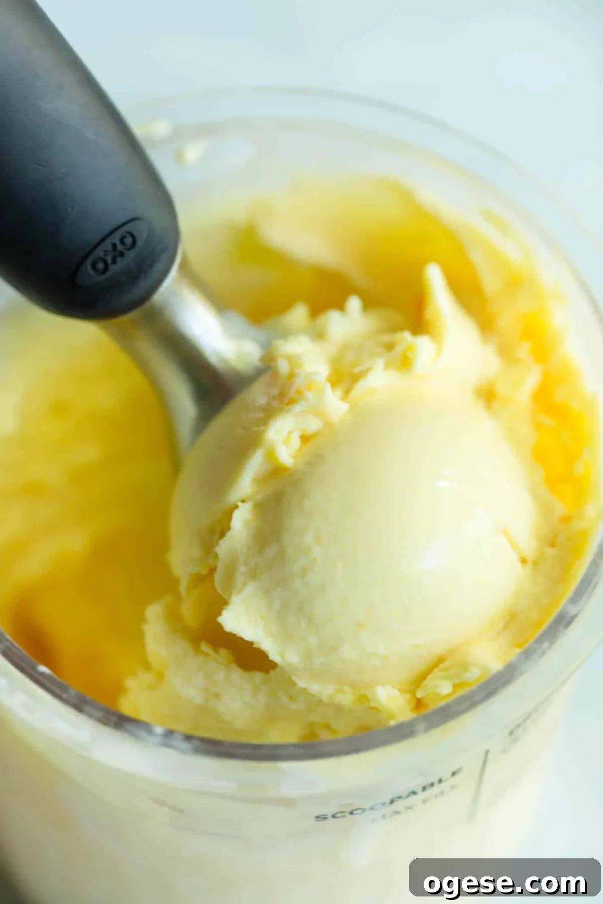 Orange Creamsicle Cottage Cheese Ice Cream Recipe 7 Orange Creamsicle Cottage Cheese Ice Cream in the Ninja Creami pint container with a scoop being taken out of it with an ice cream scoop.
