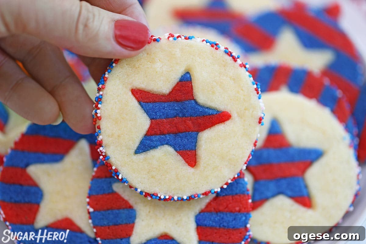 Close-up of a hand with a red nail holding a Stars and Stripes Sugar Cookie.