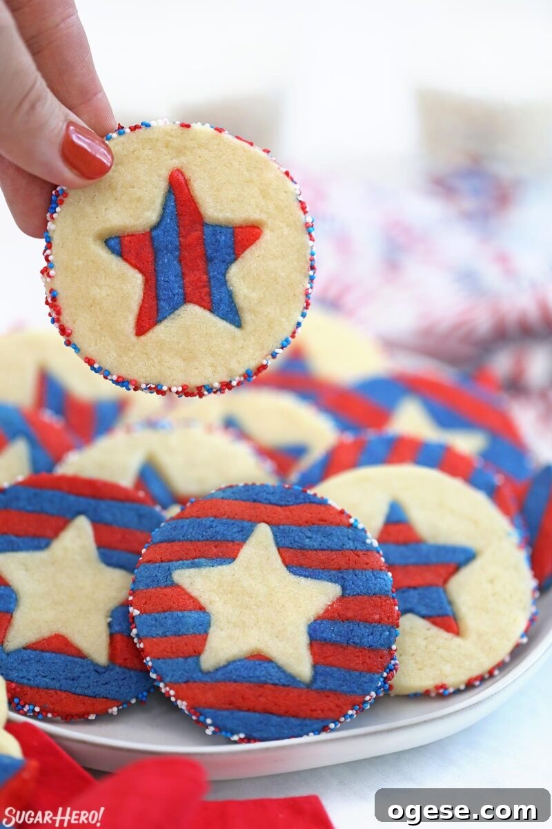 Hand holding up a Stars and Stripes Sugar Cookie from a plate of other cookies.