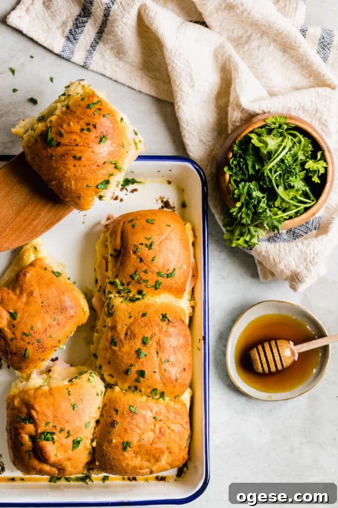 Savory Ham and Swiss Sliders with Honey-Dijon Glaze 4 A Pan Full of Ham Sandwiches Beside a Small Bowl of Fresh Honey