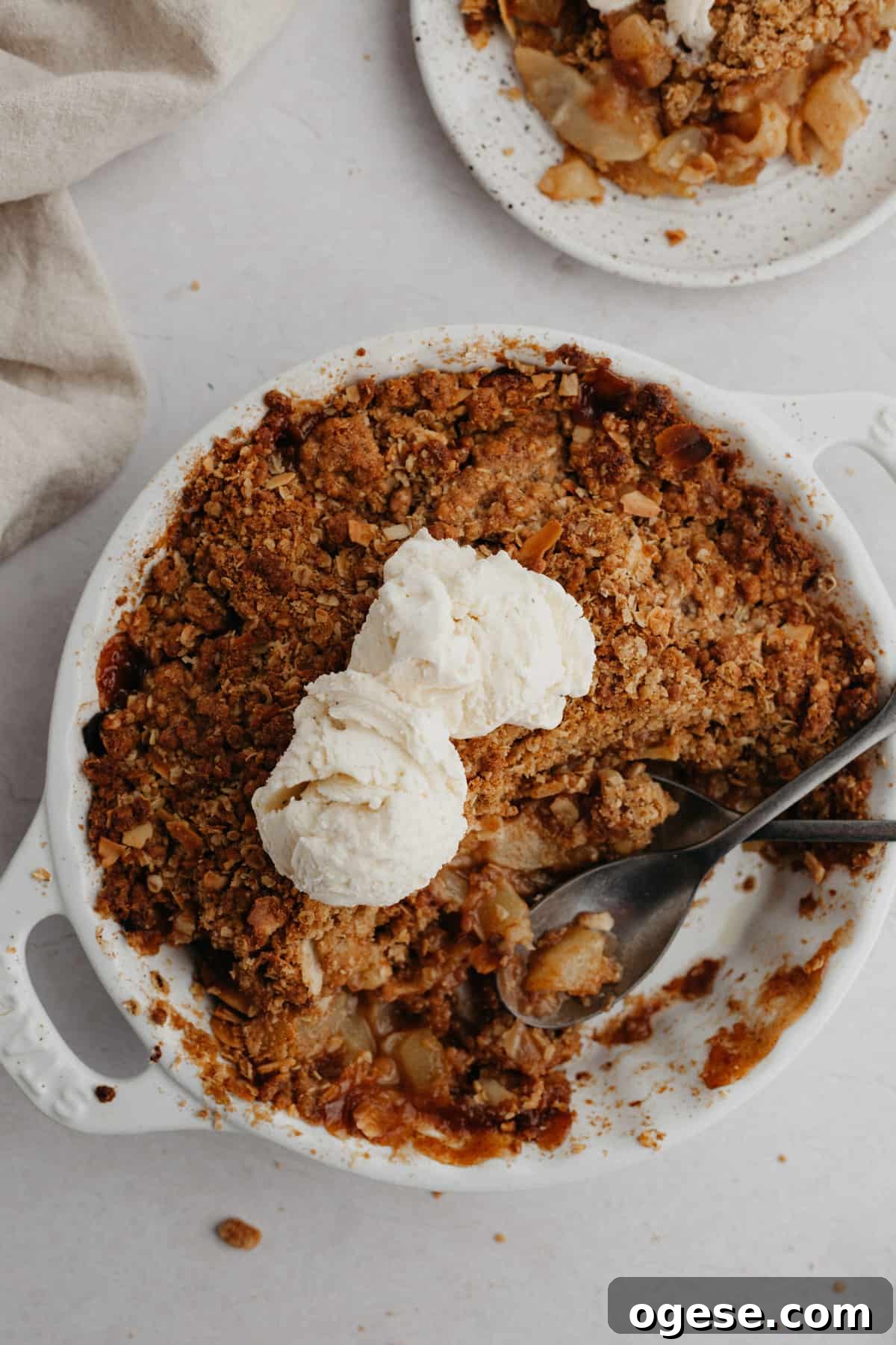 A round white ceramic dish with pear and apple crisp.