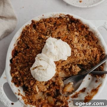 A round white ceramic dish with pear and apple crisp.