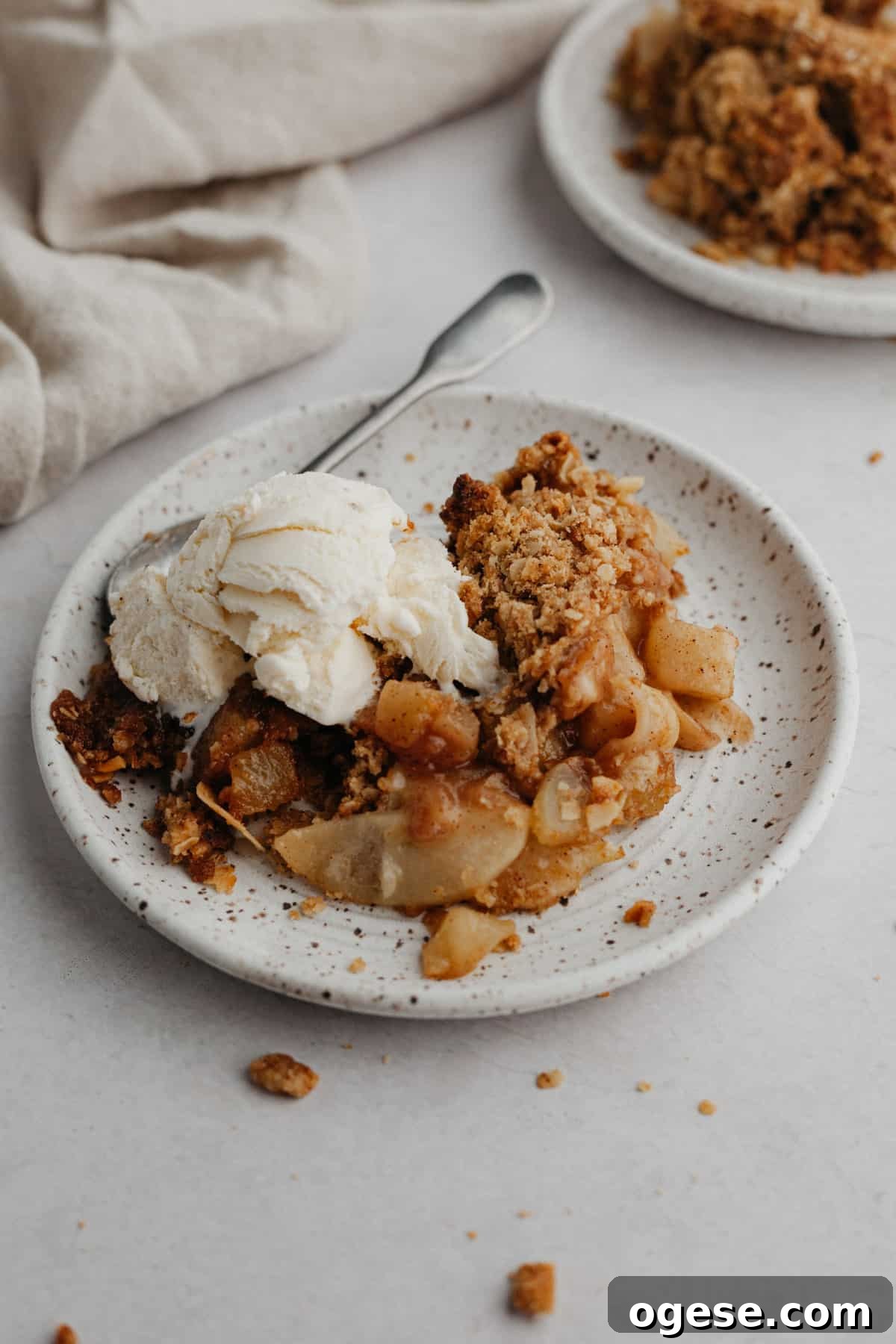 A plate of pear crisp, the plate is on top of a beige linen.