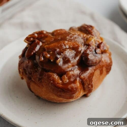 A caramel cinnamon roll on a small beige plate.