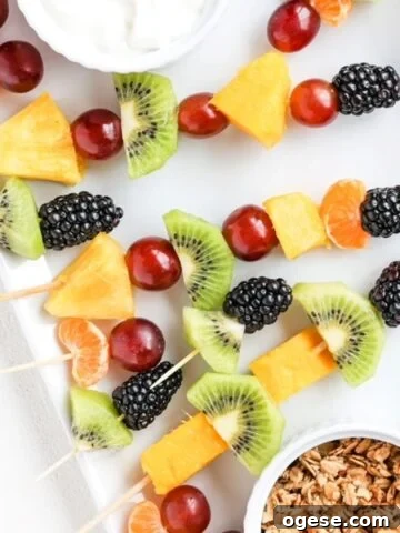 Pieces of fresh fruit on toothpicks and bamboo skewers on a white plate.