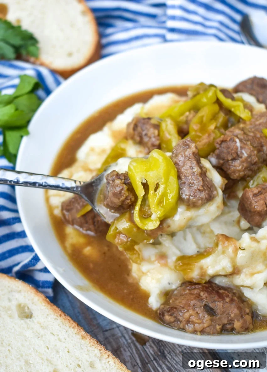 Mississippi Pot Roast Stew Recipe: Slow-Cooked Tender Beef 7 a silver spoon in a white bowl filled with instant pot mississippi roast stew over mashed potatoes