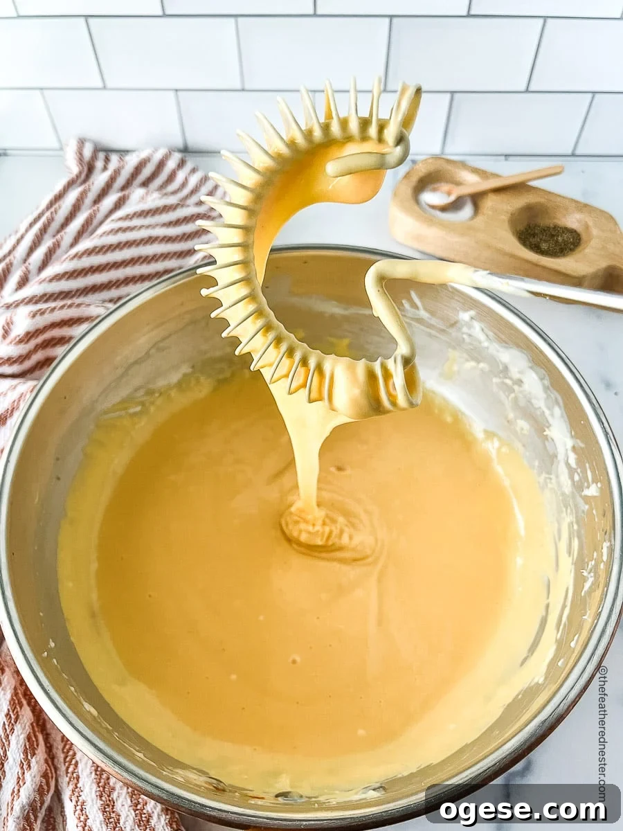 Creamy melted cheddar cheese in a bowl and on a whisk.