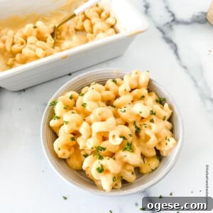 Creamy velveeta cheese sauce mixed with macaroni on a bowl and in a serving platter at the back.