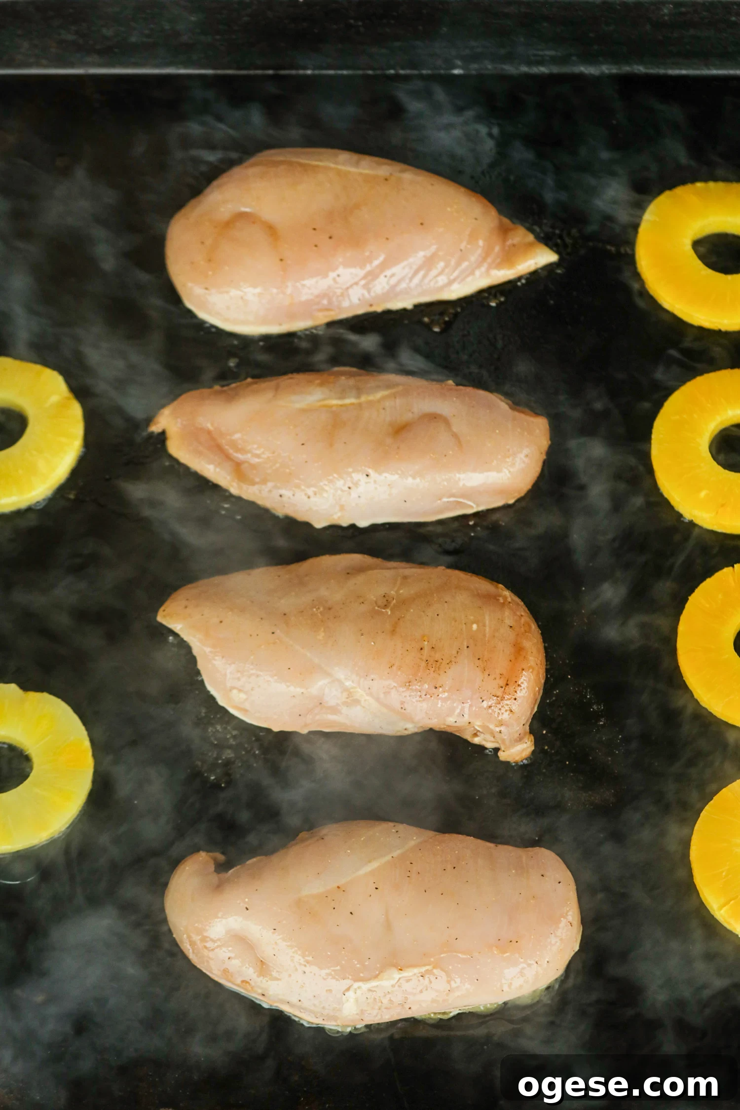 Grilled Pineapple Chicken with Tangy Glaze and Charred Pineapple 6 The image shows chicken breasts searing with pineapple slices on the griddle.