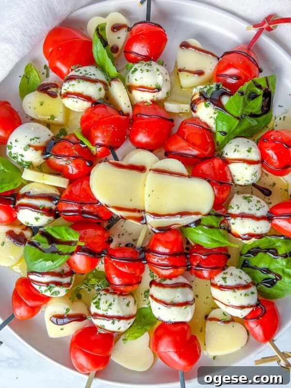Romantic Valentine's Day Appetizers to Impress Your Date 4 A plate of Valentines Appetizer caprese skewers with cherry tomatoes, mozzarella balls, basil leaves, and heart-shaped cheese slices, drizzled with balsamic glaze, arranged beautifully on a white dish.