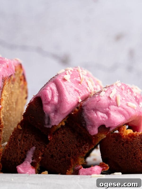 Romantic Valentine's Day Appetizers to Impress Your Date 6 A loaf cake with vibrant pink frosting is partly sliced, revealing its moist interior. Crumbs and bits of frosting are scattered around on a light-colored surface, contrasting with the rustic background.