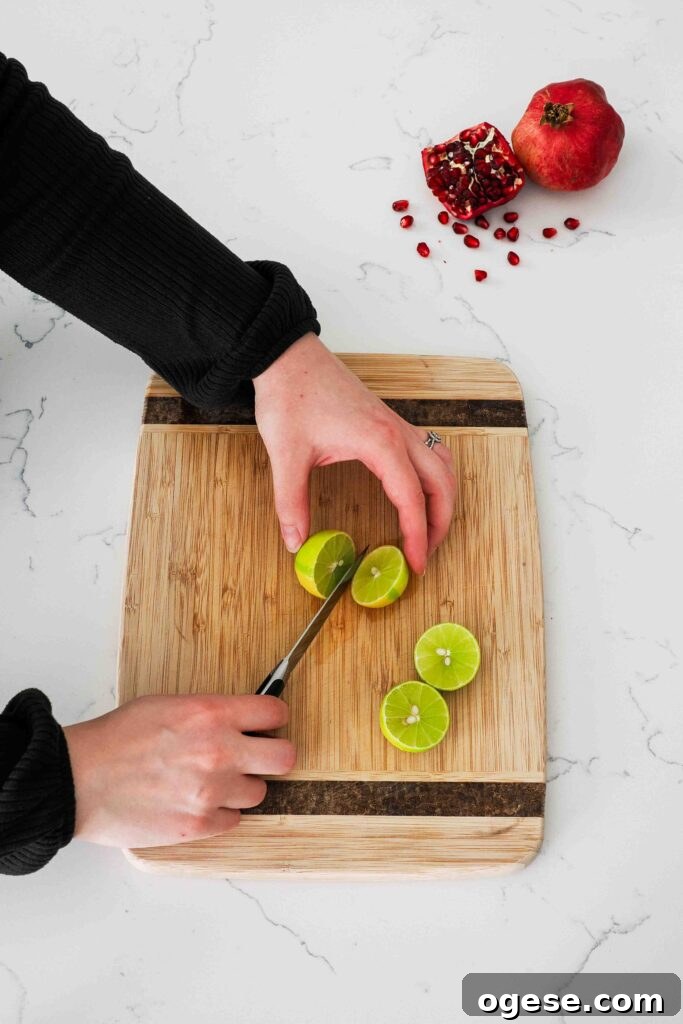 Small limes are cut in half on a cutting board.