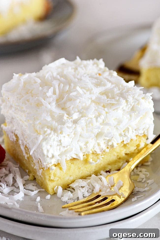 Moist Coconut Cake Recipe with Video Tutorial 7 cake with coconut frosting and a fork on a plate
