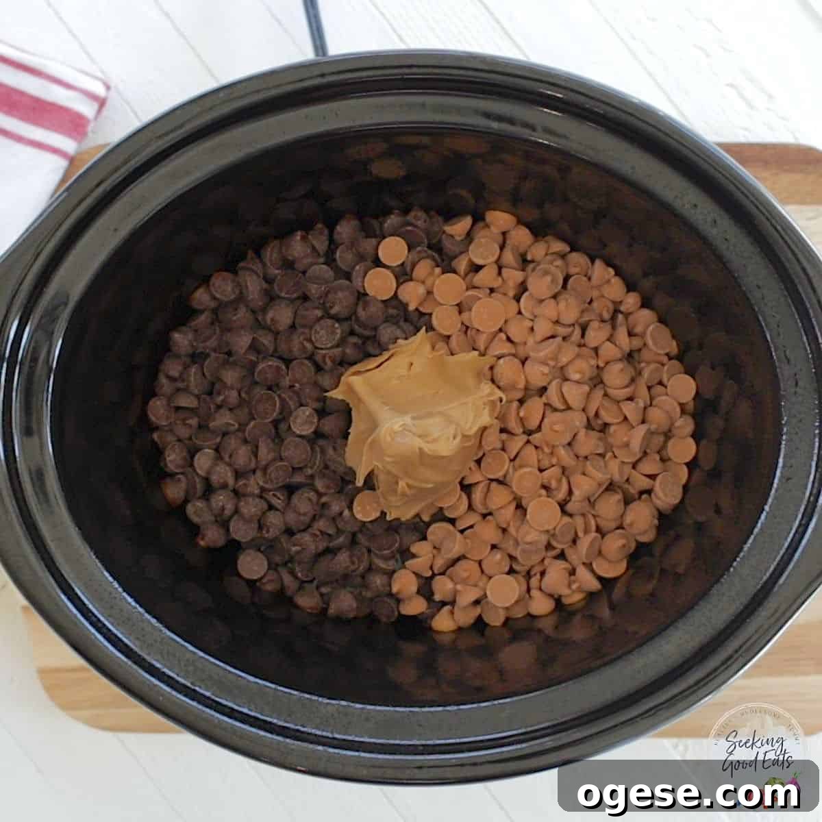 4-Ingredient Crockpot Peanut Clusters Recipe 4 Crockpot peanut clusters cooking chocolate and butterscotch chips with peanut butter in a black oval crockpot.