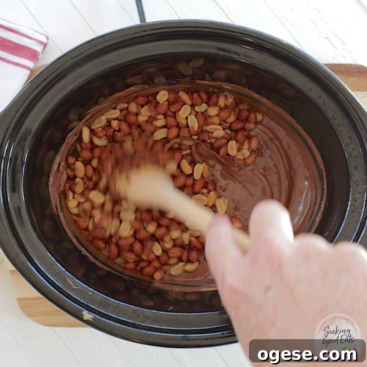 4-Ingredient Crockpot Peanut Clusters Recipe 5 Stirring the slow cooker chocolate peanut clusters recipe in an oval black slow cooker.