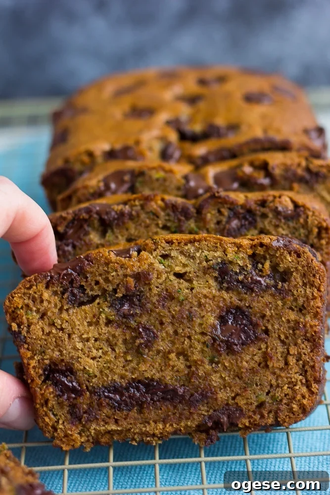 vegan zucchini bread with a hand grabbing one slice