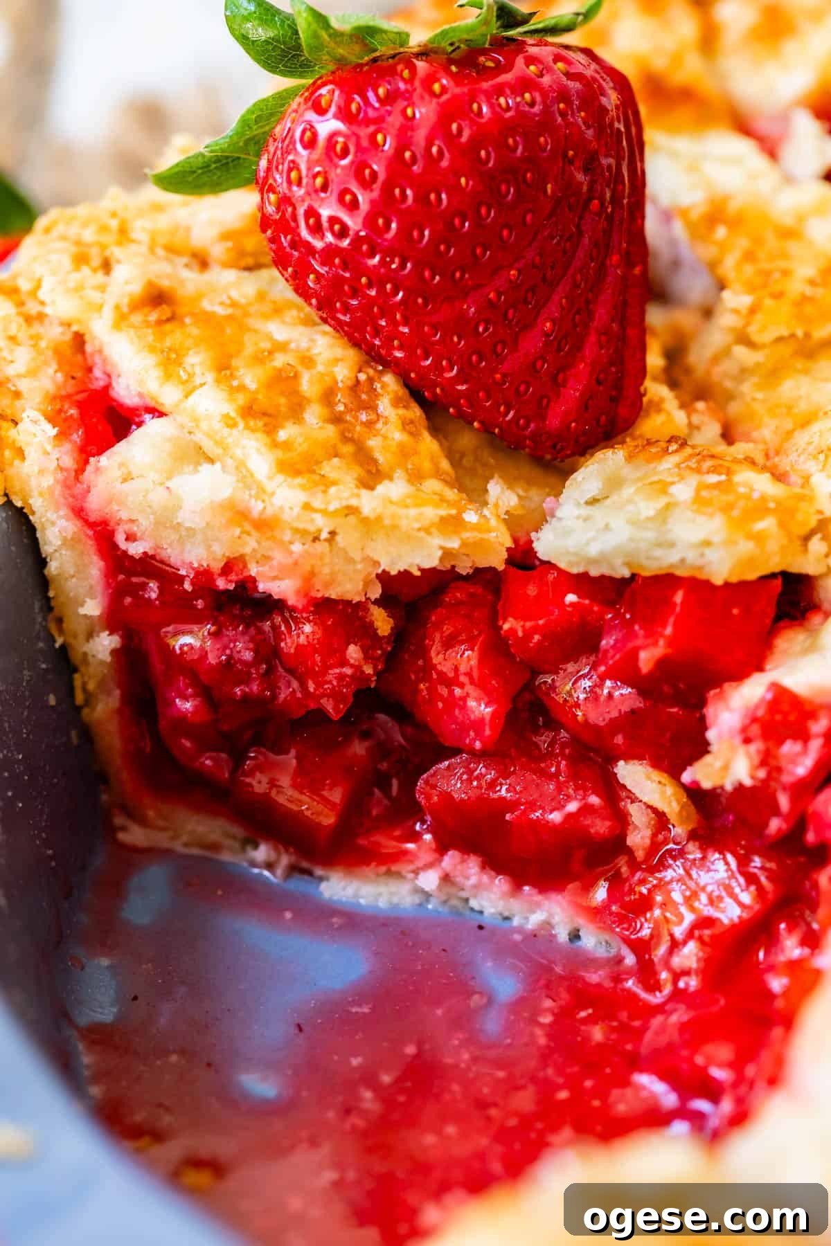 looking at the side of a piece of pie with all the strawberry and rhubarb filling showing.