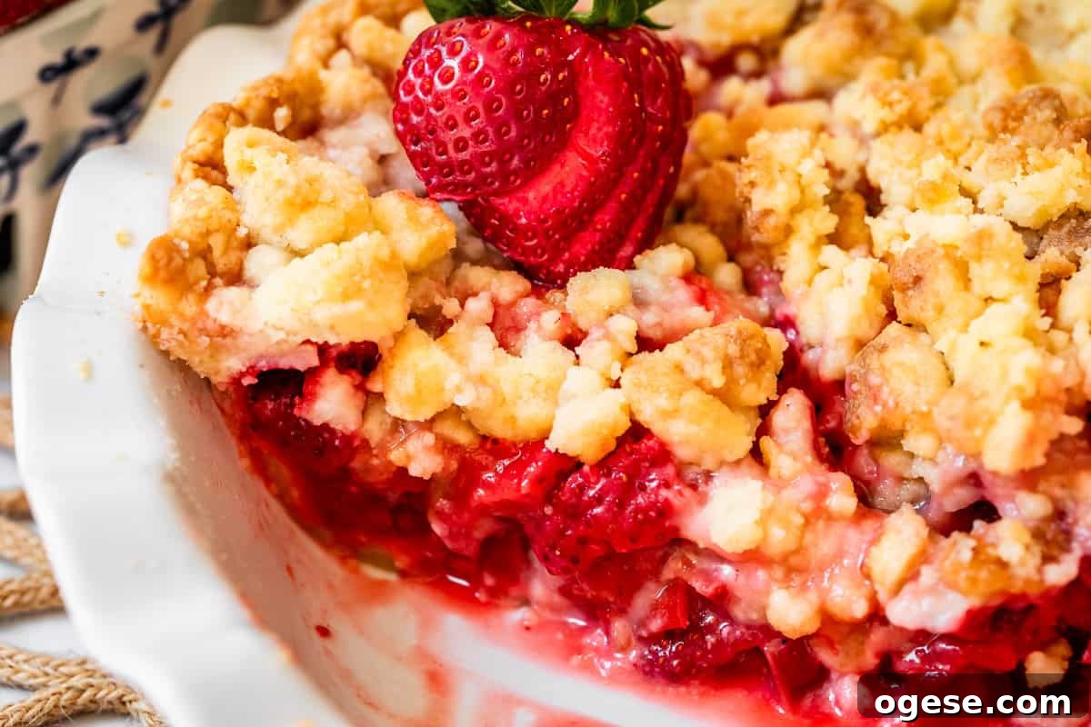 baked strawberry rhubarb pie with crumble topping in pie pan with slice removed.