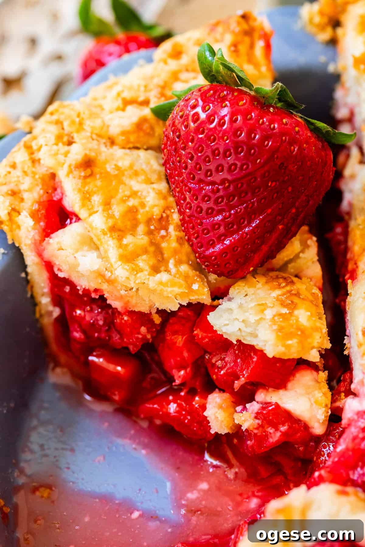 piece of lattice crust strawberry and rhubarb pie with lots of filling and fresh strawberry garnish.