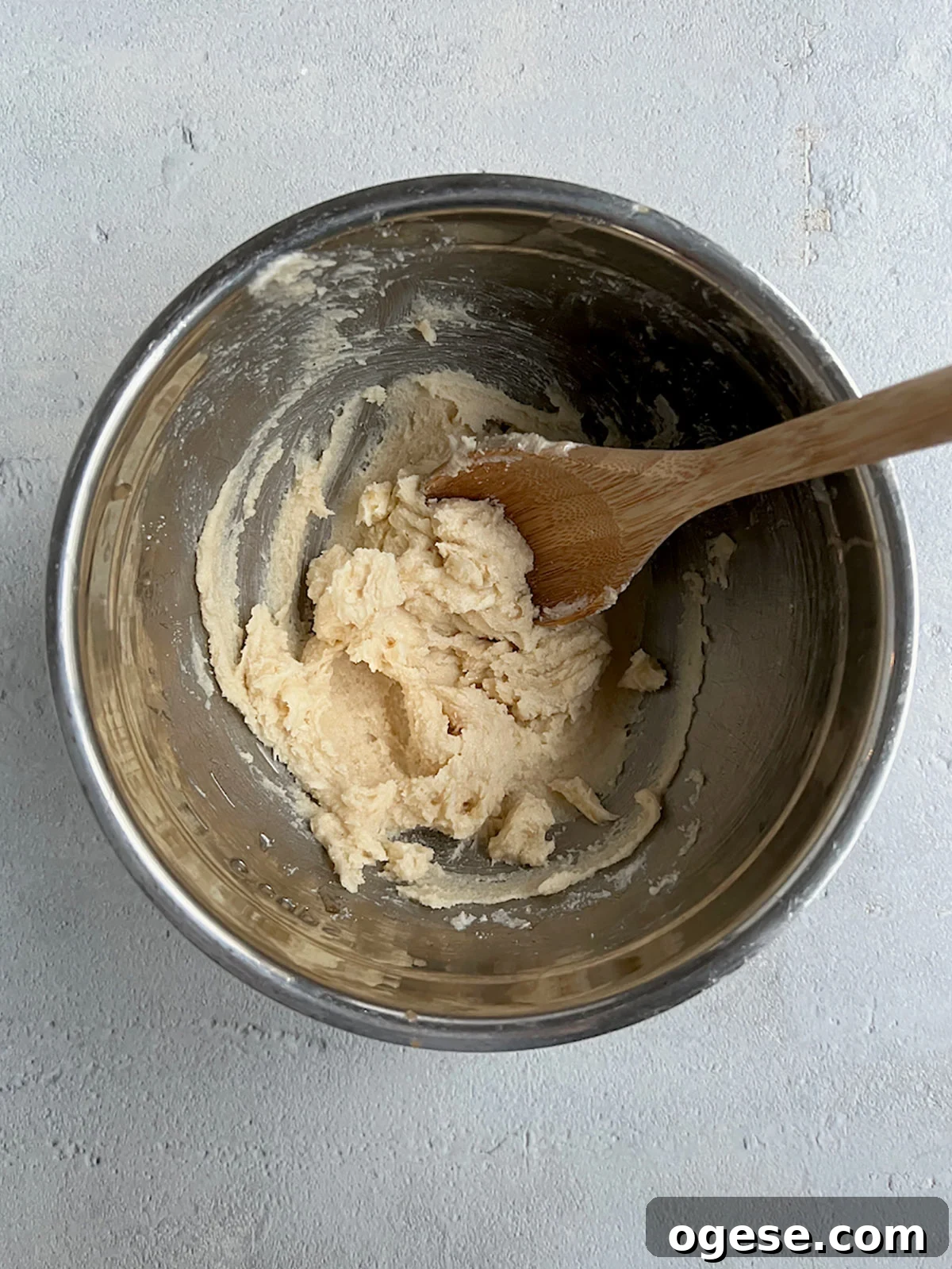 Creamed butter and sugar in a bowl with wooden spoon.