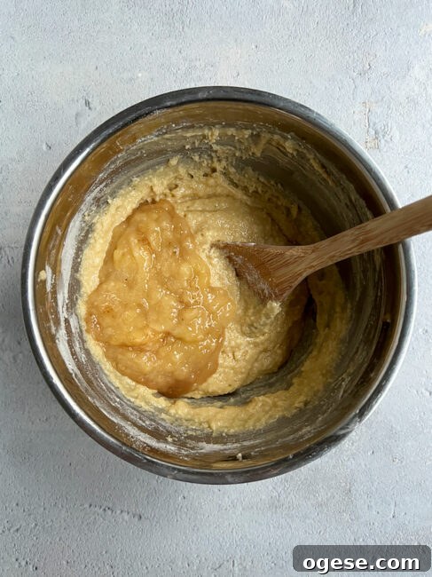Adding banana to banana bread batter.