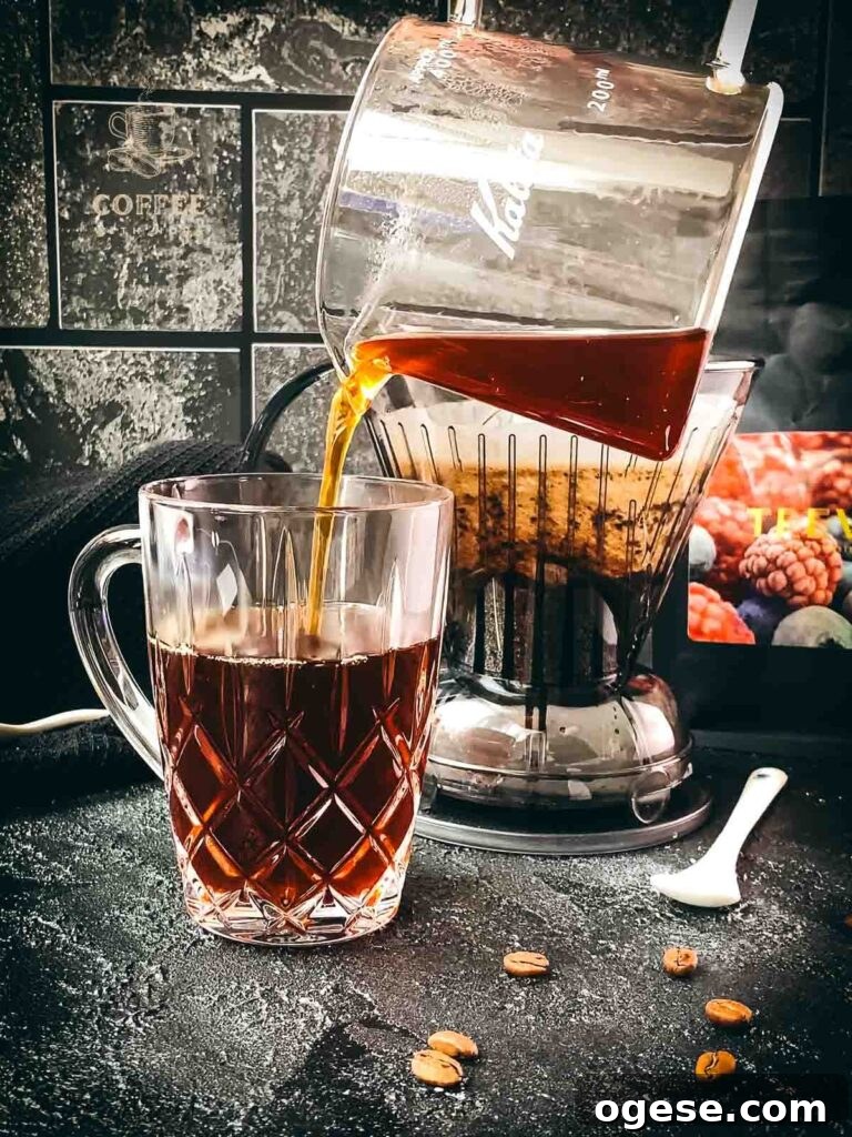 Innovative Coffee Dripper for Richer Pour-Over Flavor 7 Pouring freshly brewed coffee from a glass carafe into a glass serving mug.