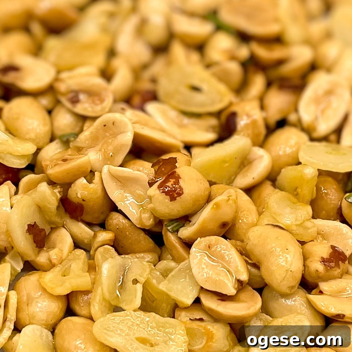 Closeup of roasted salted peanuts with toasted garlic and rosemary.