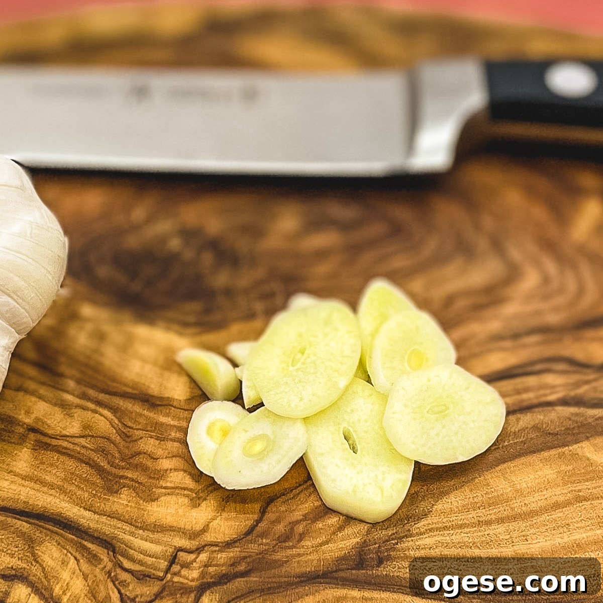 Sliced garlic on a wooden cutting board.