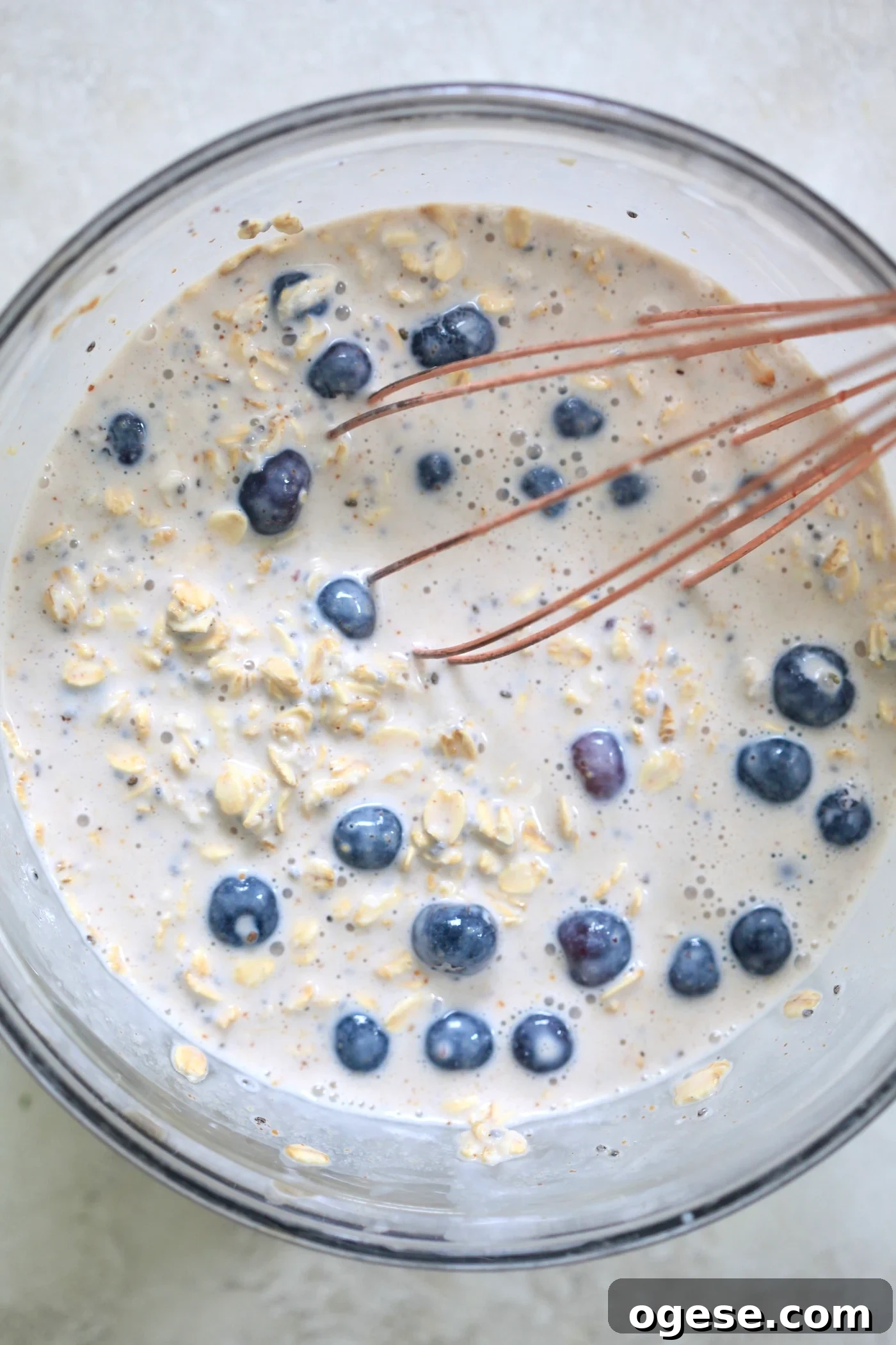 whisked oatmeal with blueberries in mixing bowl