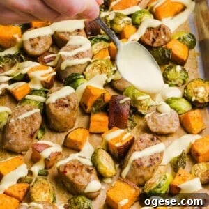 One-Pan Lemon Salmon and Orzo Recipe 13 Chicken sausage sheet pan dinner with yogurt honey mustard being drizzled over top.