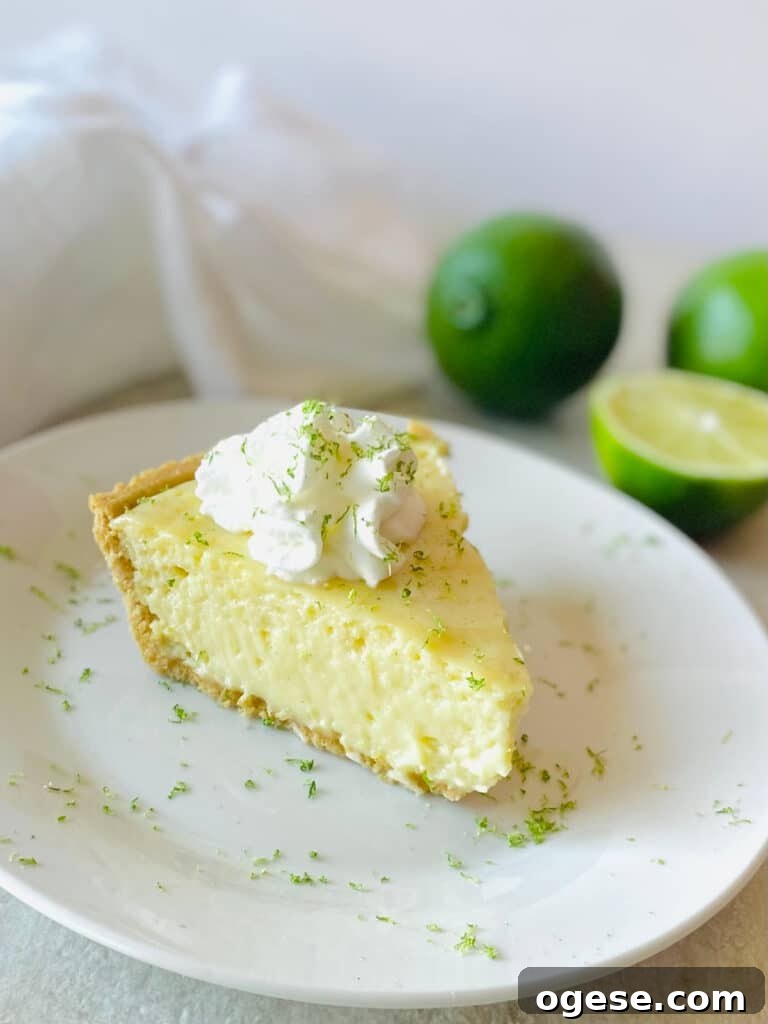 gluten free key lime pie on a plate next to limes topped with whipped cream and lime zest